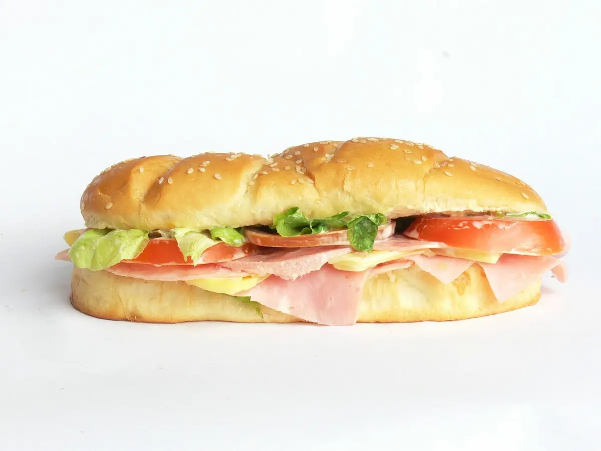 Ein Baguettesandwich, belegt mit Satat, Tomatenscheibenm gekochtem Schinken und Käse