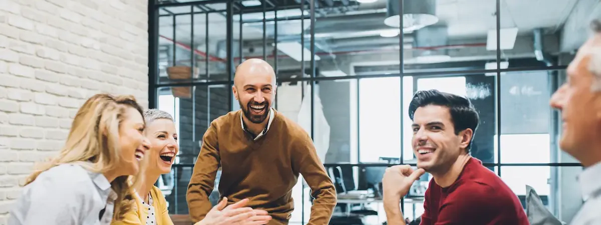 Fünf Kolleginnen und Kollegen lachen gemeinsam in einer Besprechung
